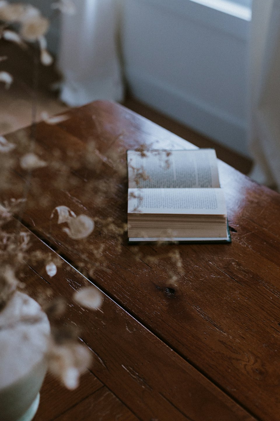 Ein offenes Buch liegt auf einem rustikalen Holztisch.